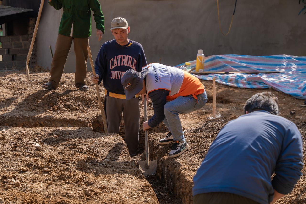 services-03 Volunteers working together to dig a trench at a construction site in daylight.